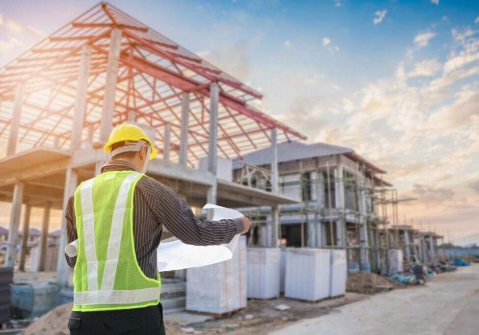 Construction worker reviewing plans at a building site during sunset.