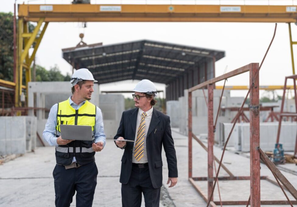 Businessman and security officer wearing paper hats at a construction site.